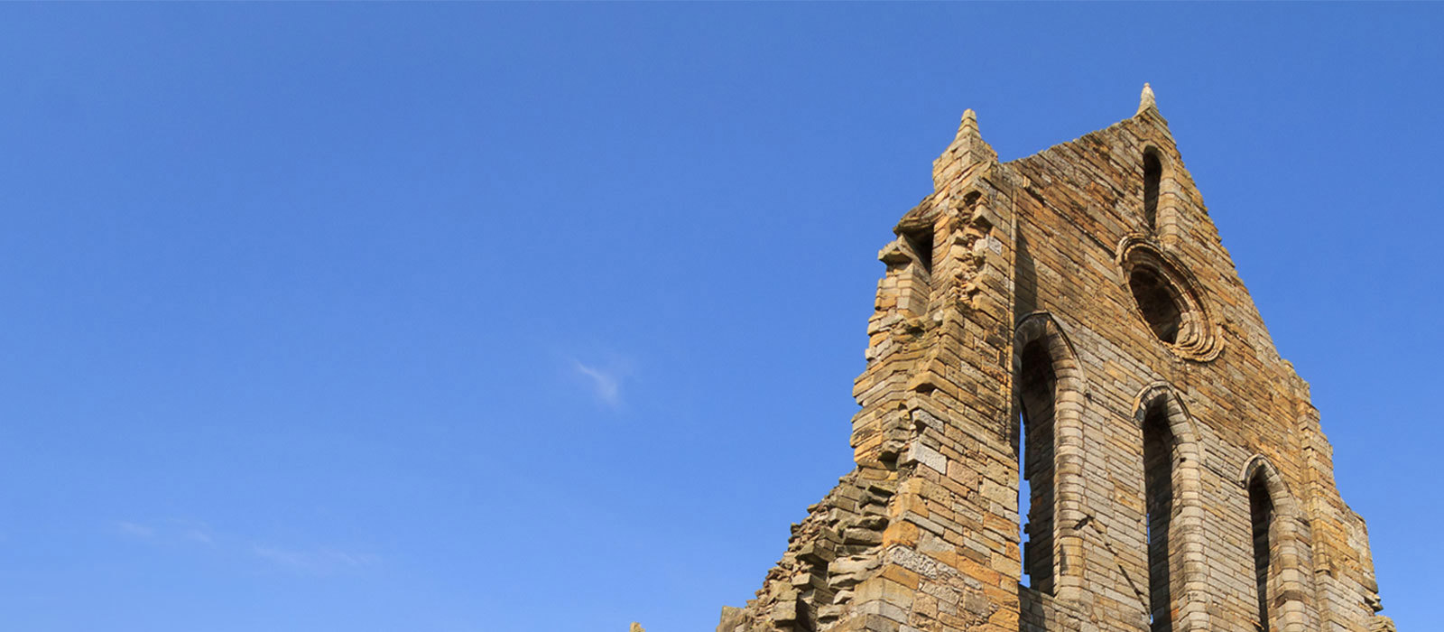The ruins of Kilwinning Abbey against a blue sky